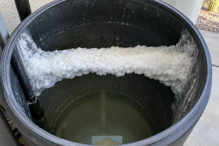Looking into a brine tank with a hard crusted salt bridge across the middle and a gap of empty space beneath it
